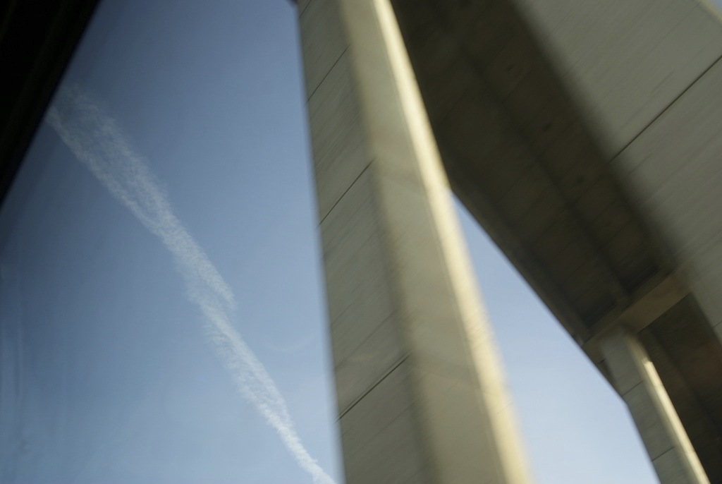 a blurred image of an overhead bridge against a blue sky